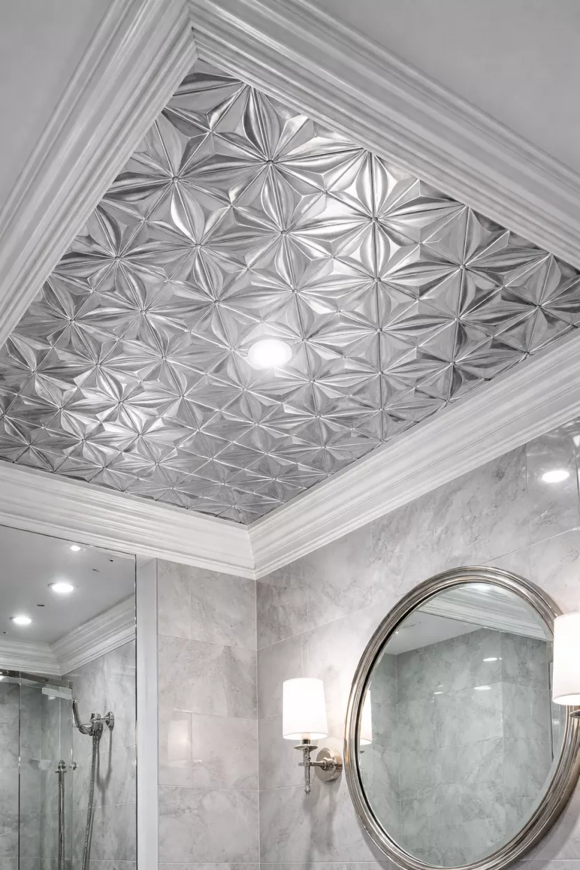 A realistic photo of a bathroom ceiling covered in silver metallic wallpaper with a geometric pattern and white crown molding.