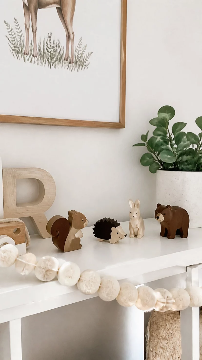A super-realistic photo of a nursery shelf with a chunky cream wool garland draped across the front edge, surrounding a few wooden forest animal figurines, everyday social media post aesthetic, photorealistic, high-quality mobile photography, shot on an iPhone 14