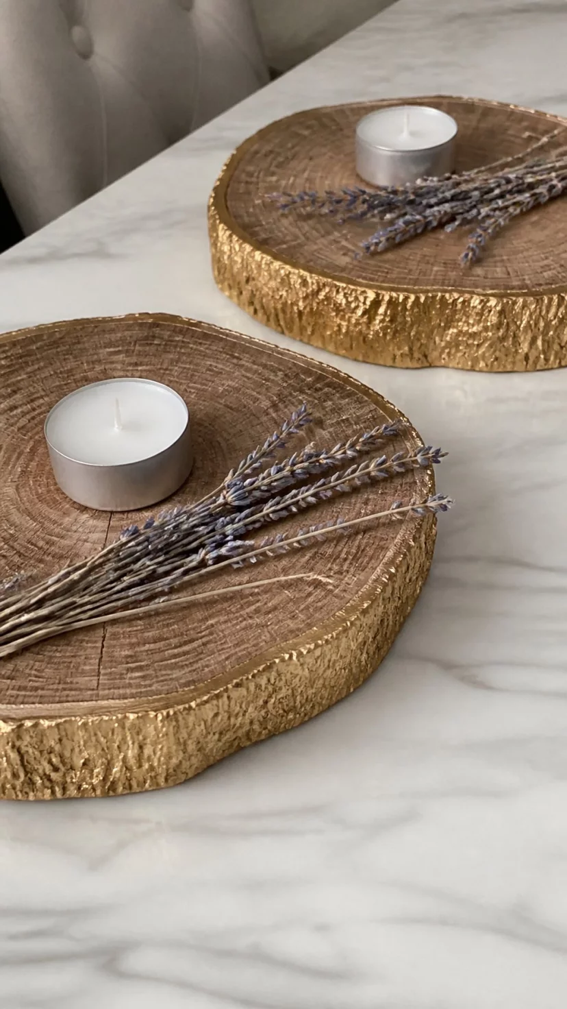 Metallic Dipped Log Slices A super-realistic photo of a minimalist dining table showcasing thick natural wood log slices with their edges painted in shimmering gold leaf, the slices acting as pedestals for small white tea lights and sprigs of dried lavender, a clean white marble tabletop visible beneath the rustic wood, everyday social media post aesthetic, photorealistic, high-quality mobile photography, shot on an iPhone 14