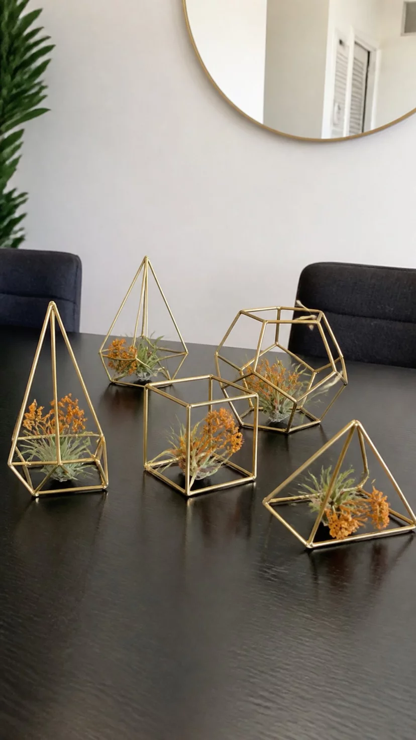 Geometric Metal Frames With Air Plants A super-realistic photo of a modern black dining table featuring several gold geometric wire frames of different shapes, small green air plants and tiny orange dried flowers nestled inside the frames, minimalist setting with plenty of white space, everyday social media post aesthetic, photorealistic, high-quality mobile photography, shot on an iPhone 14