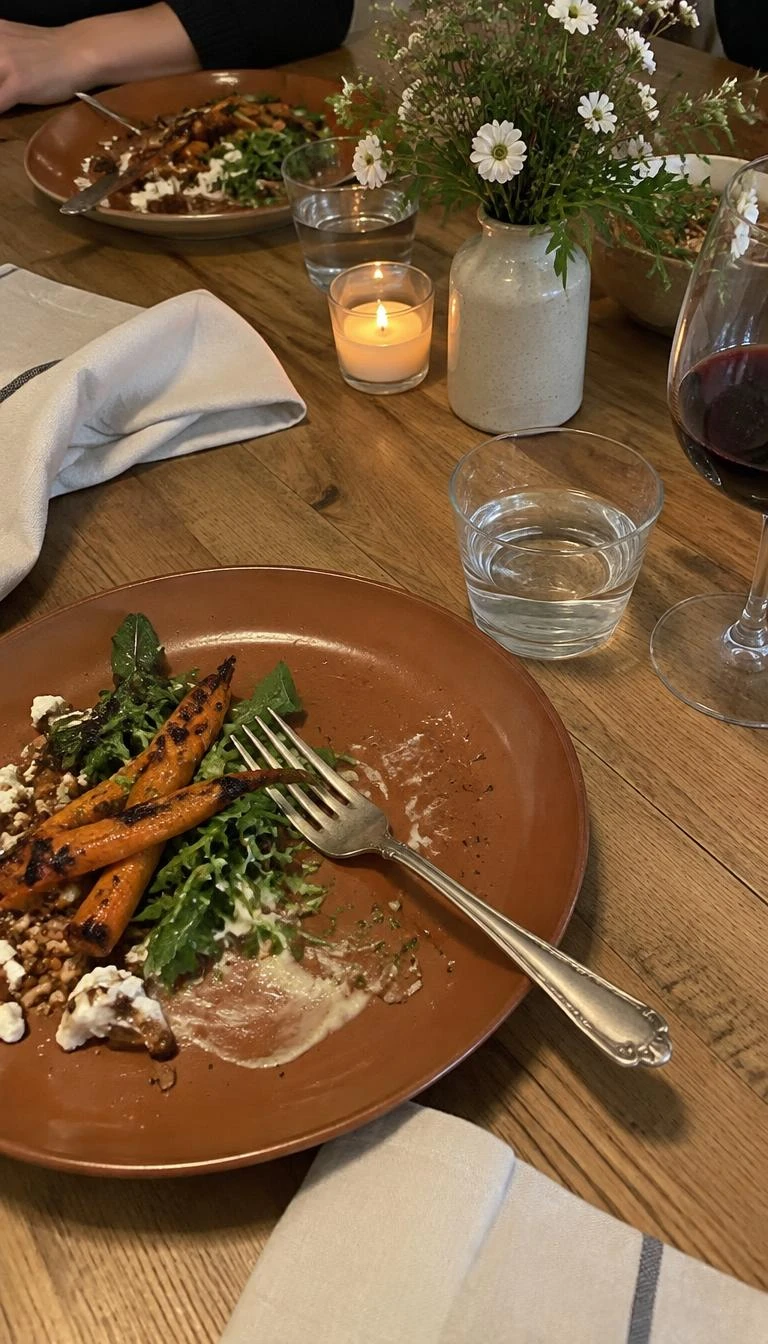 A candid, realistic iPhone photograph of an intimate dining table, featuring warm terracotta dinner plates paired with tarnished vintage silver forks, unbleached cotton napkins, and a plain timber surface, natural indoor lighting.