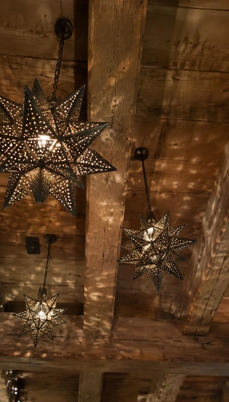 A candid, realistic iPhone photograph looking up at exposed timber ceiling beams, where punctured tin star lanterns hang on twisted brown cords, casting delicate pinprick light patterns across rough wood planks.